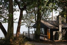 a small cabin in the woods next to water