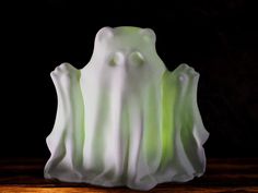 a green and white vase sitting on top of a wooden table