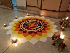 several candles are lit on the floor in front of an elephant and flower design that appears to be made out of paper