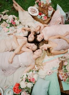 a group of women laying on top of a lush green field next to each other