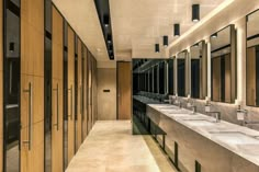 a long row of sinks in a bathroom with mirrors on the wall and lights above them