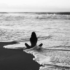 a woman sitting on top of a surfboard in the ocean next to an ocean