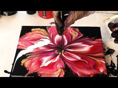 someone is painting a flower on a canvas