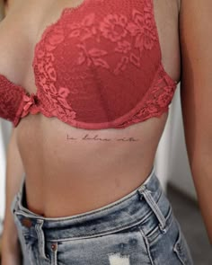 a woman wearing a red bra top with writing on her chest and the word love is written in cursive ink