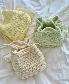 three crocheted bags sitting on top of a bed