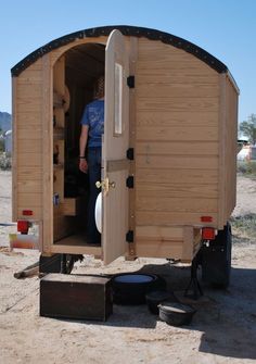 a man standing in the doorway of a small wooden trailer with its door open and it's interior opened