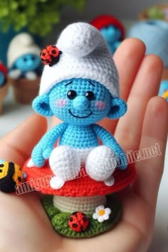 a small crocheted blue toy sitting on top of a red and white mushroom