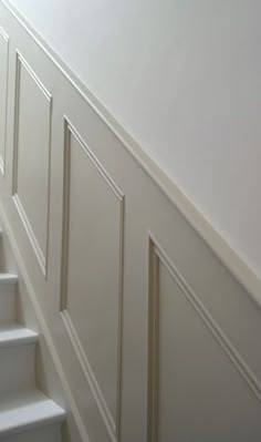 the stairs are lined with white painted paneling