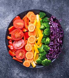 a plate filled with different types of veggies on top of a gray surface