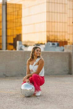 a woman sitting on the ground next to a silver ball