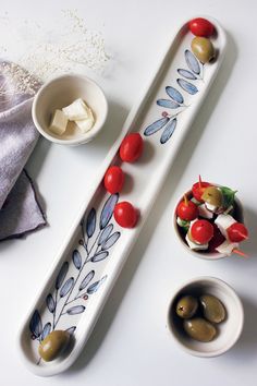 two serving trays with olives, tomatoes and cheese on them next to small bowls