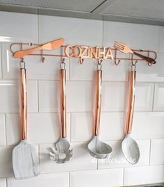 copper and white kitchen utensils hanging on the wall with name cozna