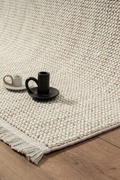 a coffee cup sitting on top of a rug next to a black plate and saucer