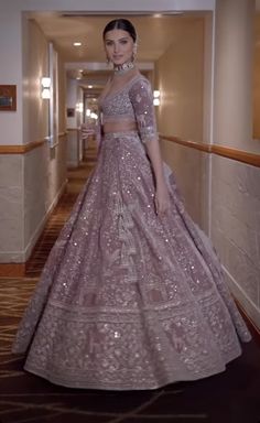 a woman standing in a hallway wearing a purple gown and matching jewelry with her hair pulled back