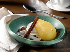 a bowl filled with ice cream and fruit on top of a wooden table next to silverware