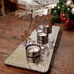 three silver candles sitting on top of a wooden table next to a christmas ornament