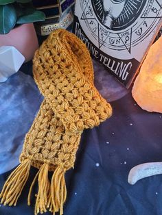 a yellow scarf sitting on top of a table next to a lit candle and book