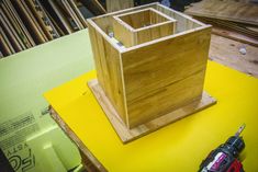 a wooden box sitting on top of a table next to a cordless driller