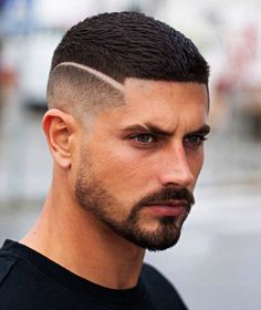 a young man with a shaved undercut looks into the camera while wearing a black t - shirt