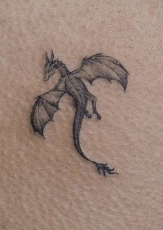 a small dragon tattoo on the back of a woman's stomach is shown in black ink