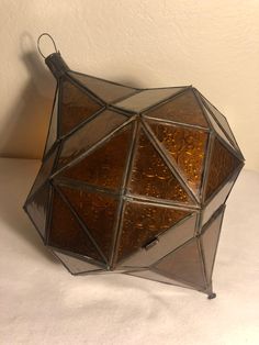 an unusual looking glass object sitting on top of a white table next to a wall