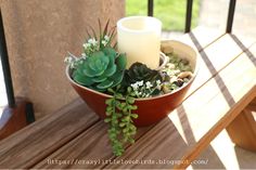 a table with a candle and succulents sitting on top of it next to a wooden bench