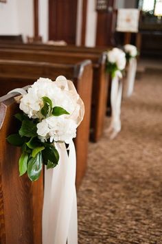 white flowers are tied to pews in a church