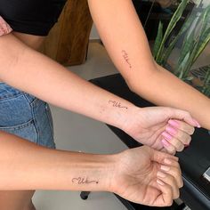 two women holding hands with writing on their arms and the words love are written in cursive font