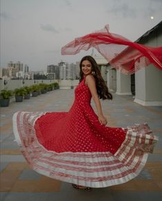 a woman in a red and white dress is posing for the camera with her hands on her hips