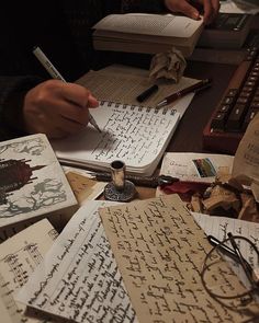 an image of someone writing on some old books with pen and eyeglasses in front of them