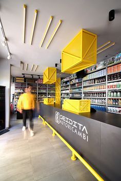 a man walking past a store filled with lots of shelves full of food and drinks