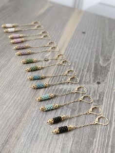 a row of different colored beaded earrings sitting on top of a wooden table