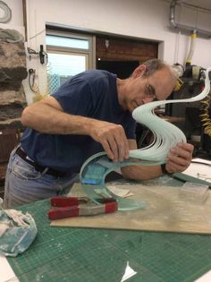 a man working on some kind of object in a room with other items around him