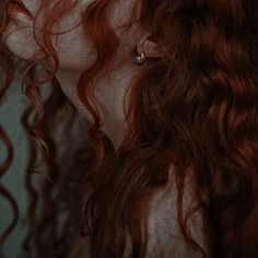 a woman with long red hair is staring into the distance