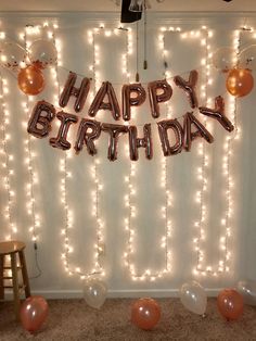 a birthday party with balloons and lights on the wall