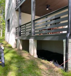 the back side of a house with a large porch and railing on it's sides