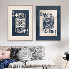 two playing cards are hanging on the wall above a couch in a room with white walls