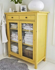 an image of a yellow cabinet with towels on top and other items in the background