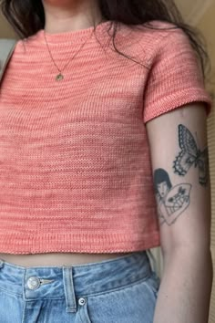 a woman with a butterfly tattoo on her left arm, wearing jeans and a pink top