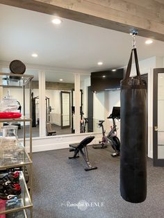 a gym with exercise equipment and mirrors in the back wall, including a punching bag