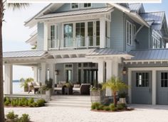 a large blue house sitting on top of a sandy beach