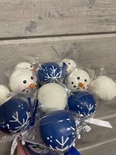 a hand holding a bunch of blue and white chocolate eggs with snowmen on them