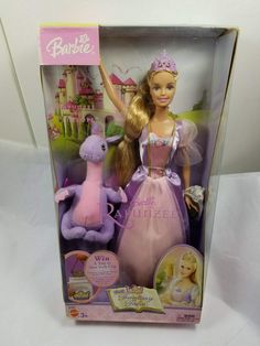 the barbie doll is in its box and has a pink dress with purple trims