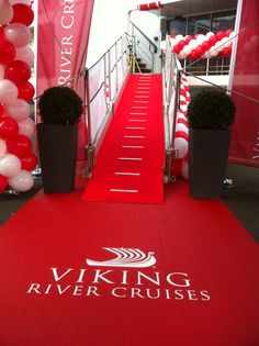 a red carpeted walkway leading up to a building with white and red balloons on it