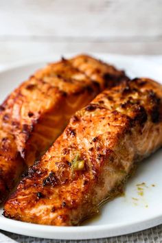 two pieces of grilled salmon on a white plate