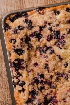 a pan filled with blueberry cobbler sitting on top of a wooden table