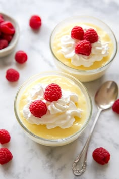 two desserts with raspberries and whipped cream in small bowls on a marble surface