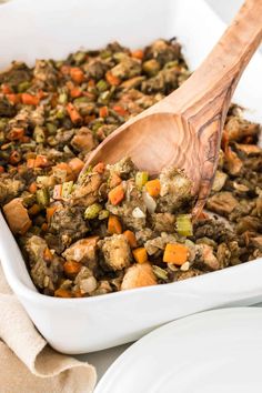 a wooden spoon in a white dish filled with stuffing