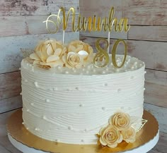 a white cake with gold decorations and the number 80 on top is sitting on a wooden table