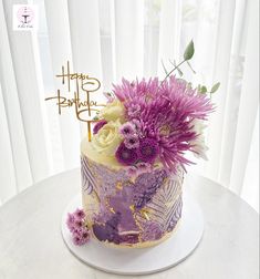 a birthday cake decorated with purple and white flowers